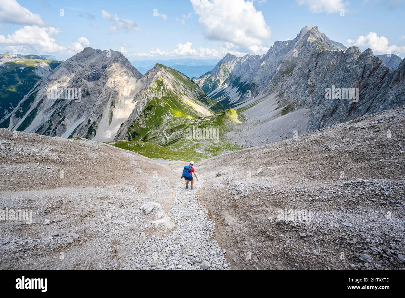 Hiker descends over a boulder field to the Lamsenjochhuette, Karwendel Mountains, Tyrol, Austria Stock Photo