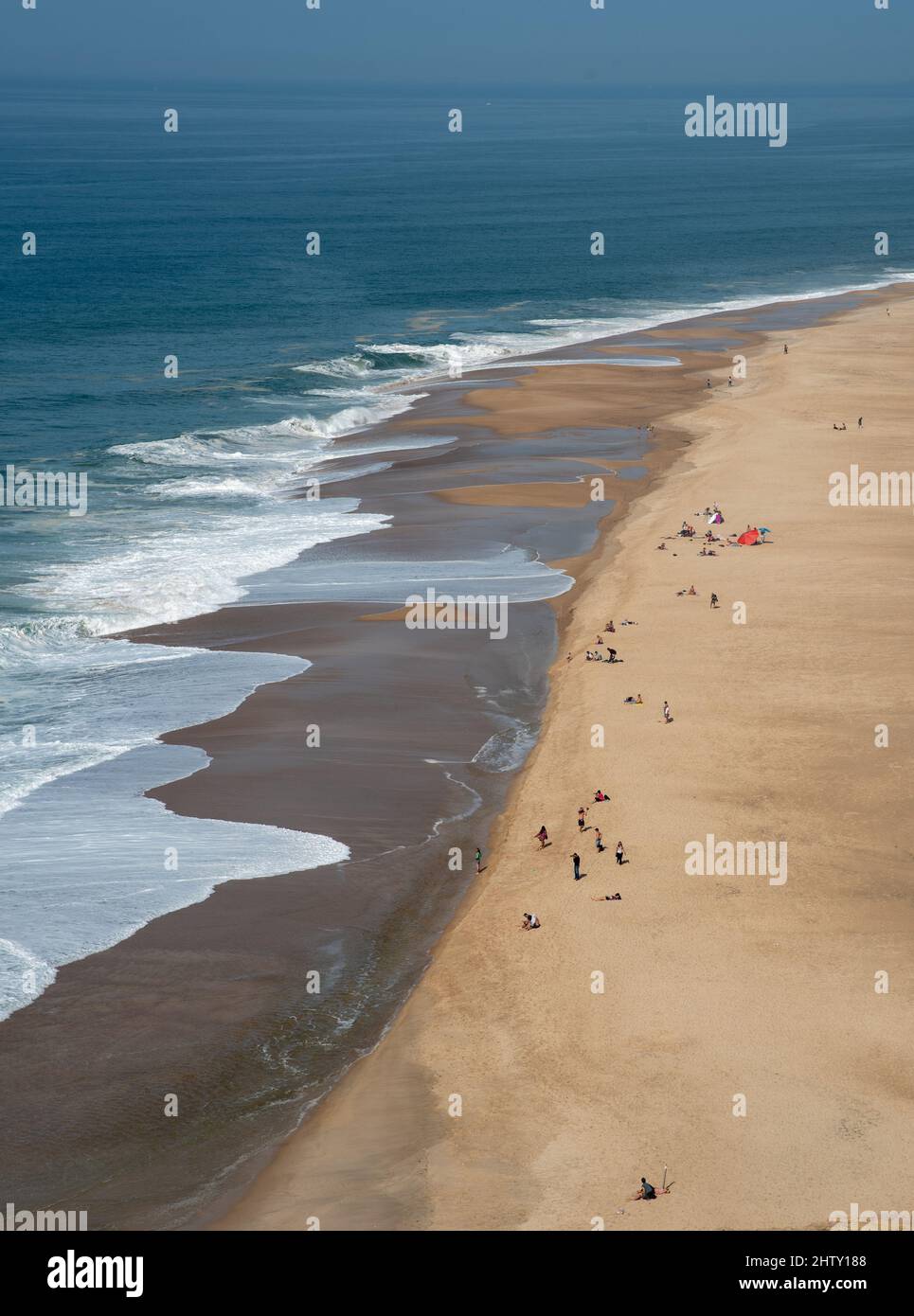 Tourist people relaxing and sunbathing a sandy tropical beach. Nazare Portugal Stock Photo
