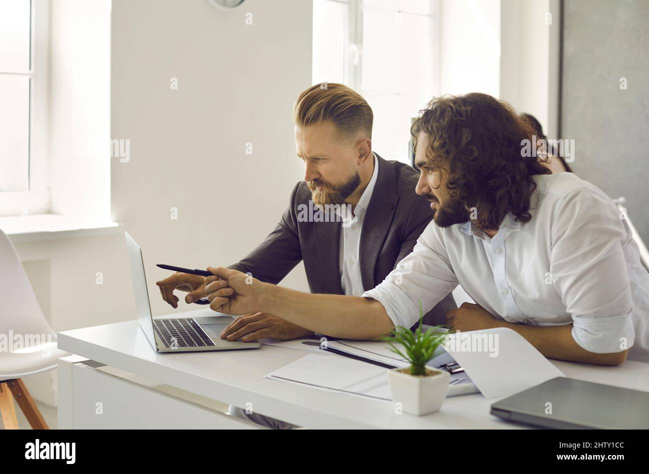 Two business people working on laptop, doing research and discussing marketing strategy Stock Photo