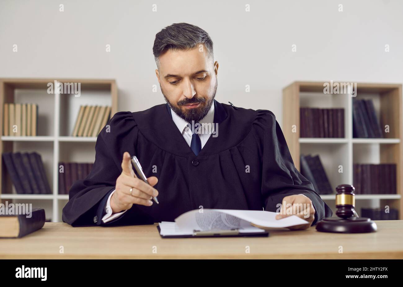 Judge, lawyer or attorney sitting at his table and reading some judicial documents Stock Photo