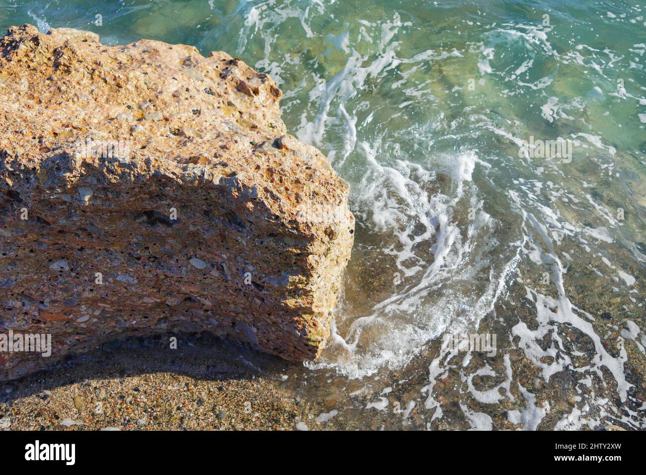 Closeup shot of the ocean waves hitting the shore with rocky beach on a ...