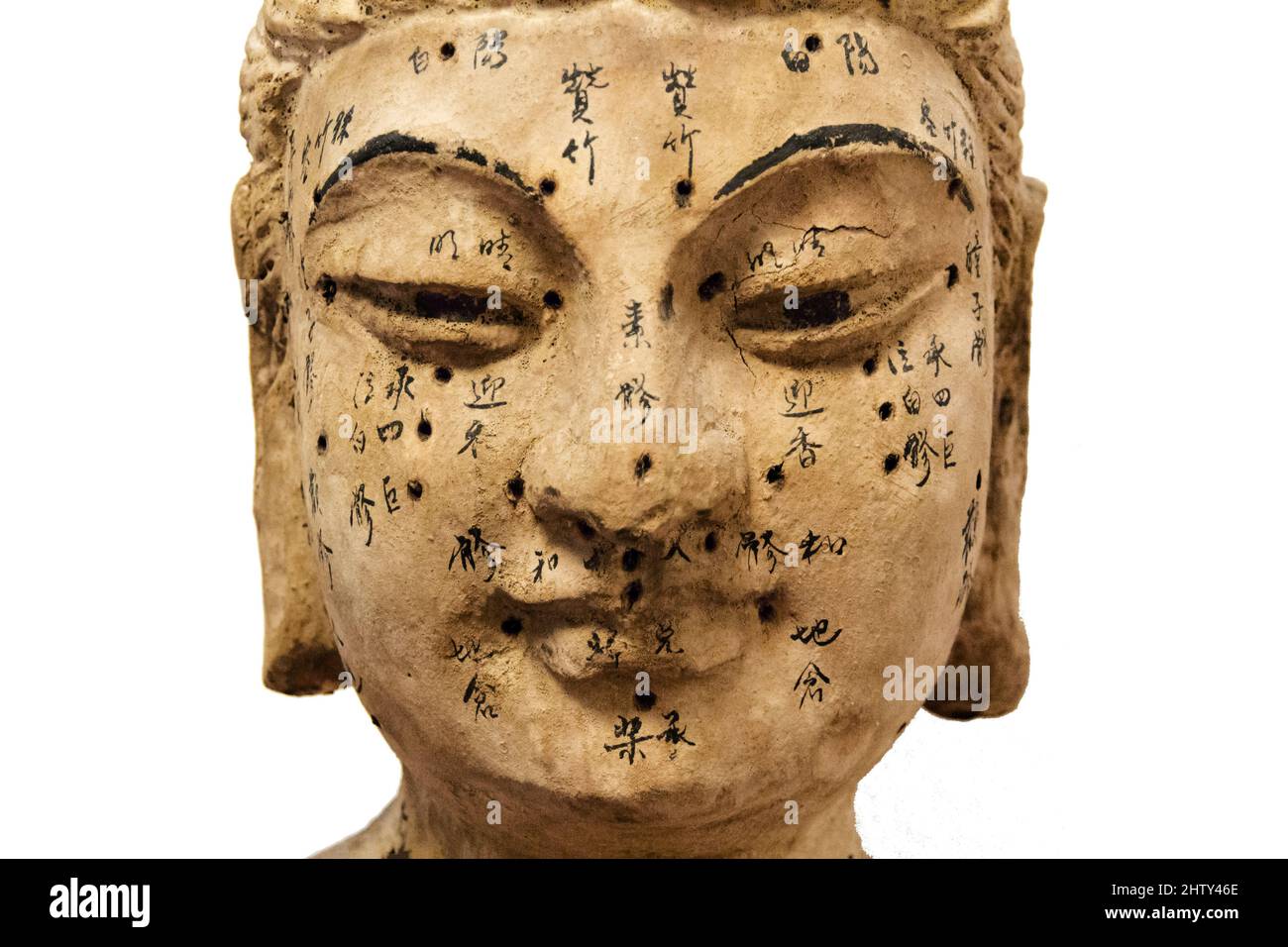 Ancient wooden female face showing acupuncture points, isolated on