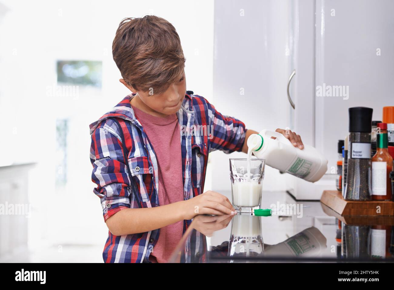 Healthy choices from a young age. A young boy pouring himself a glass of milk in the kitchen. Stock Photo