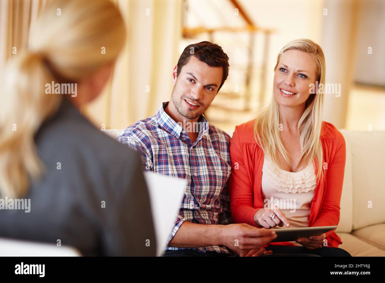 Financial planning today means great rewards tomorrow. A happy couple getting advice from a financial consultant in their home. Stock Photo