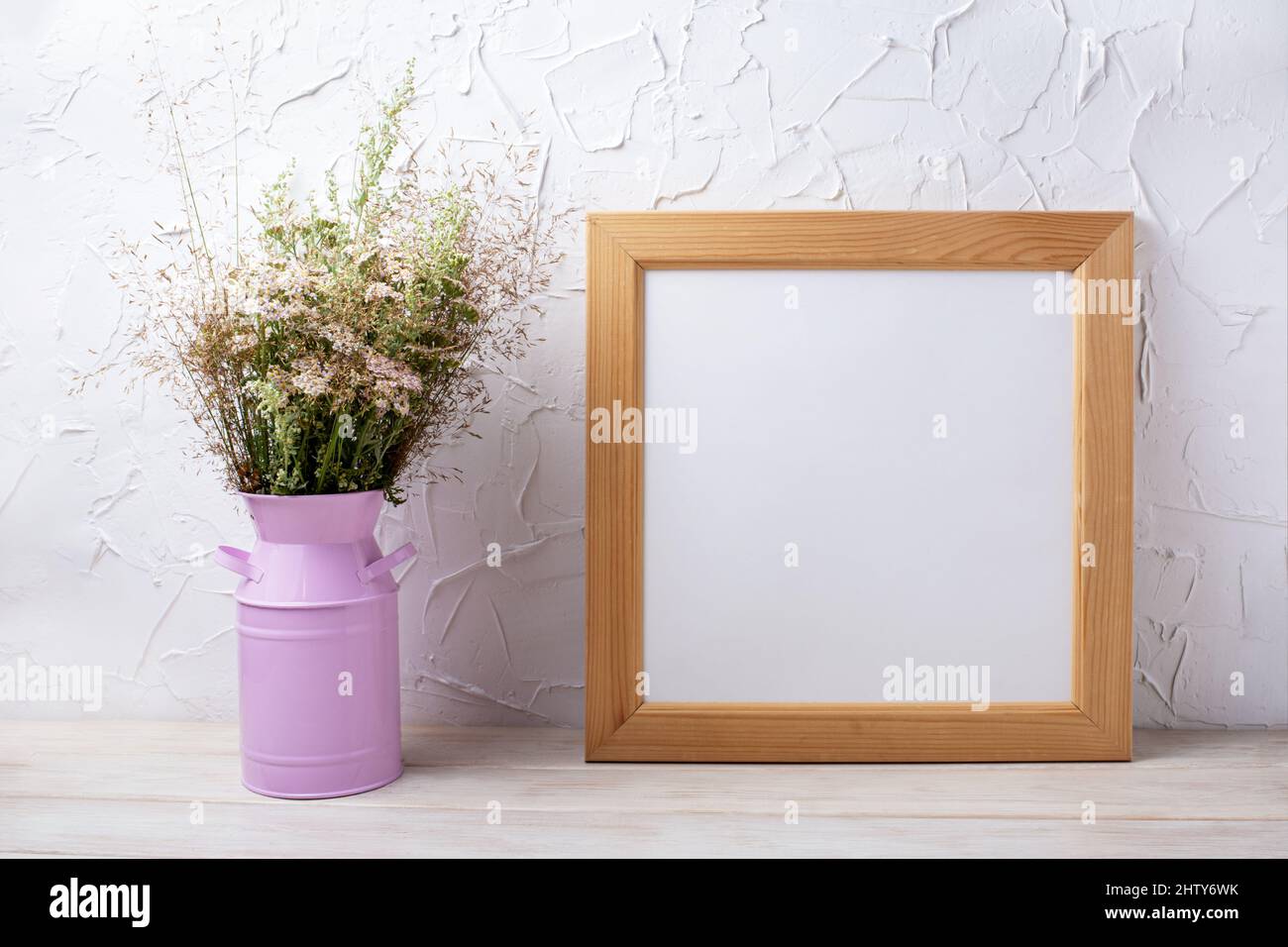 Wooden square picture frame mockup withwild flowers and grass in the pink can. Empty frame mock up for presentation design. Template framing for moder Stock Photo