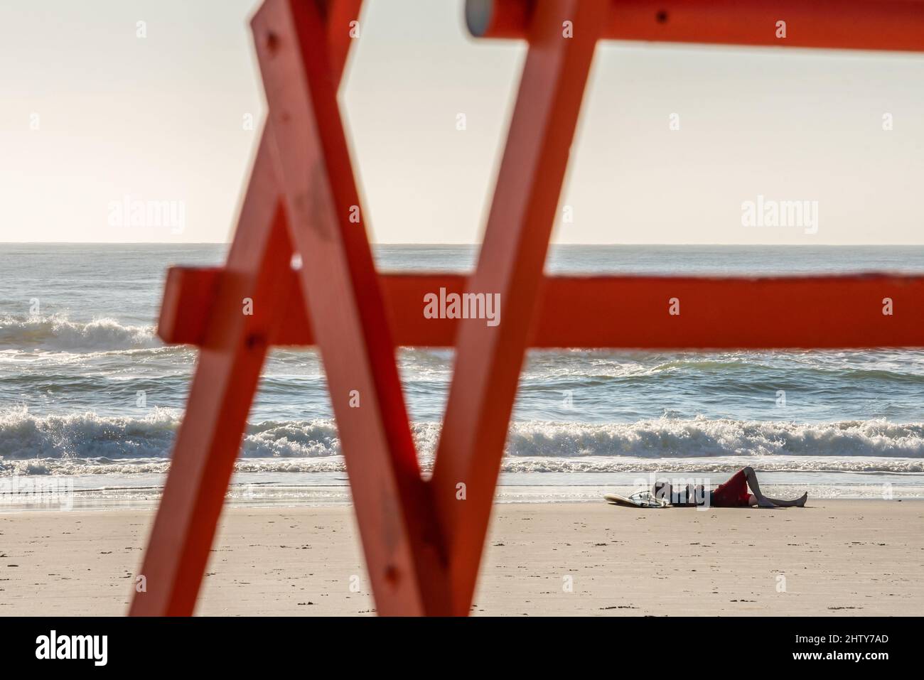 Surfing resting on the beach after an early morning surf session at