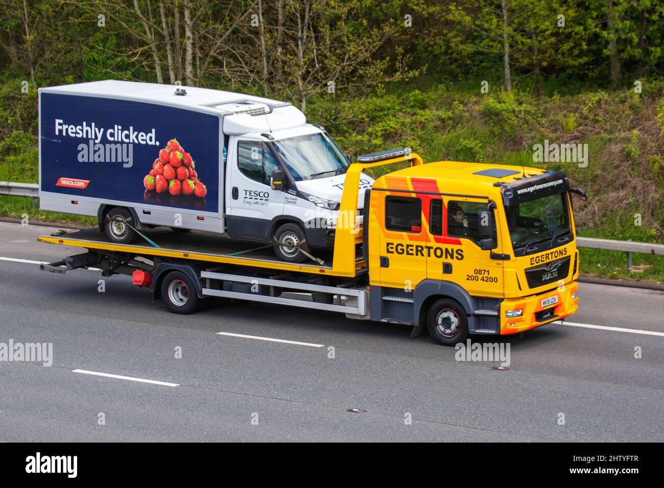 MAN 12.220 4X2 BL LX 4580CC DIESEL, driving on the M61 motorway UK carrying broken down Tesco on-line delivery grocery van. Stock Photo