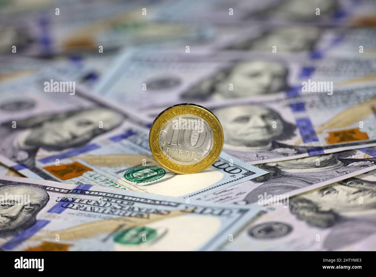 Russian rubles coin on background of US dollars. Concept of exchange rate, sanctions, falling ruble Stock Photo