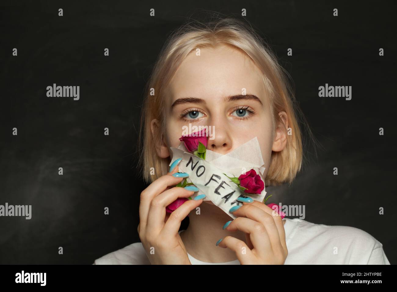 Strength teenager girl with closed mouth riping the gag off her mouth. Awkward age, growing up, harassment and domestic violence concept Stock Photo