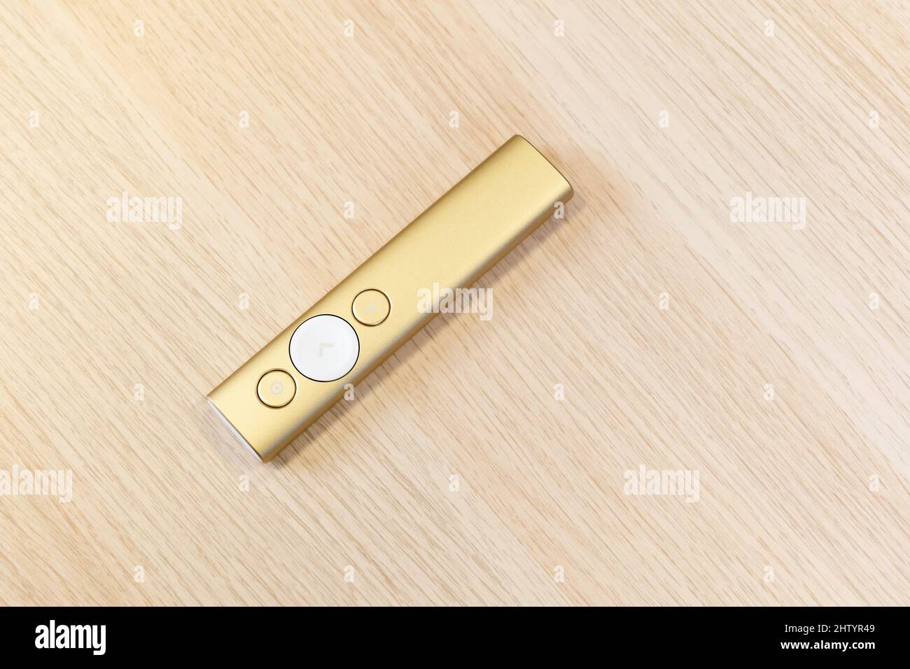 Gold presentation remote control with arrow slide changing buttons, object laying on a wooden table, closeup, top view, nobody. Lecture, talk or semin Stock Photo