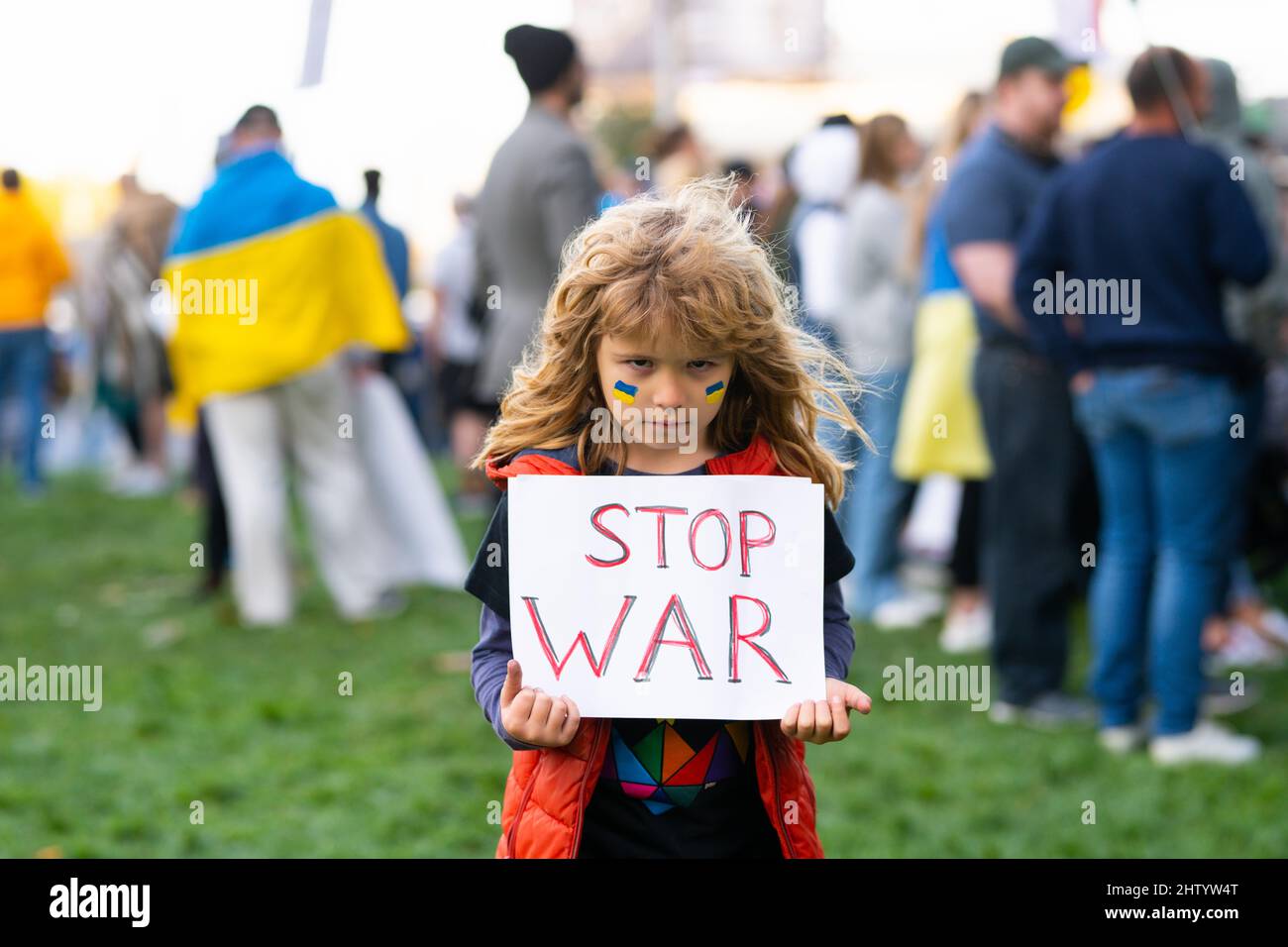 Young kid holding a poster with Stop war message, activism and human rights movement, outdoor lifestyle. Child carries a sign Stop war. Russian Stock Photo