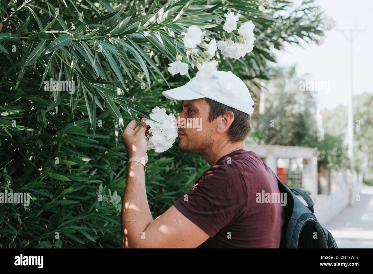 mature real candid man traveler enjoys the scent of a flowers in hand holding on a summer journey everyday moment. concept of stereotypes-free positiv Stock Photo