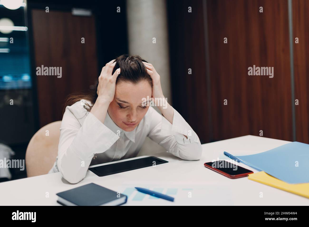 Sad businesswoman sit and hold head with his hands at office table. Concept economic sanctions, financial crisis and business bankruptcy Stock Photo