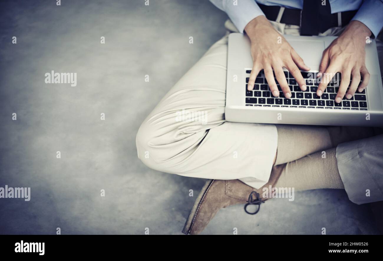 Connected in more ways than one. High angle shot of a businessman sitting on a floor using his laptop. Stock Photo