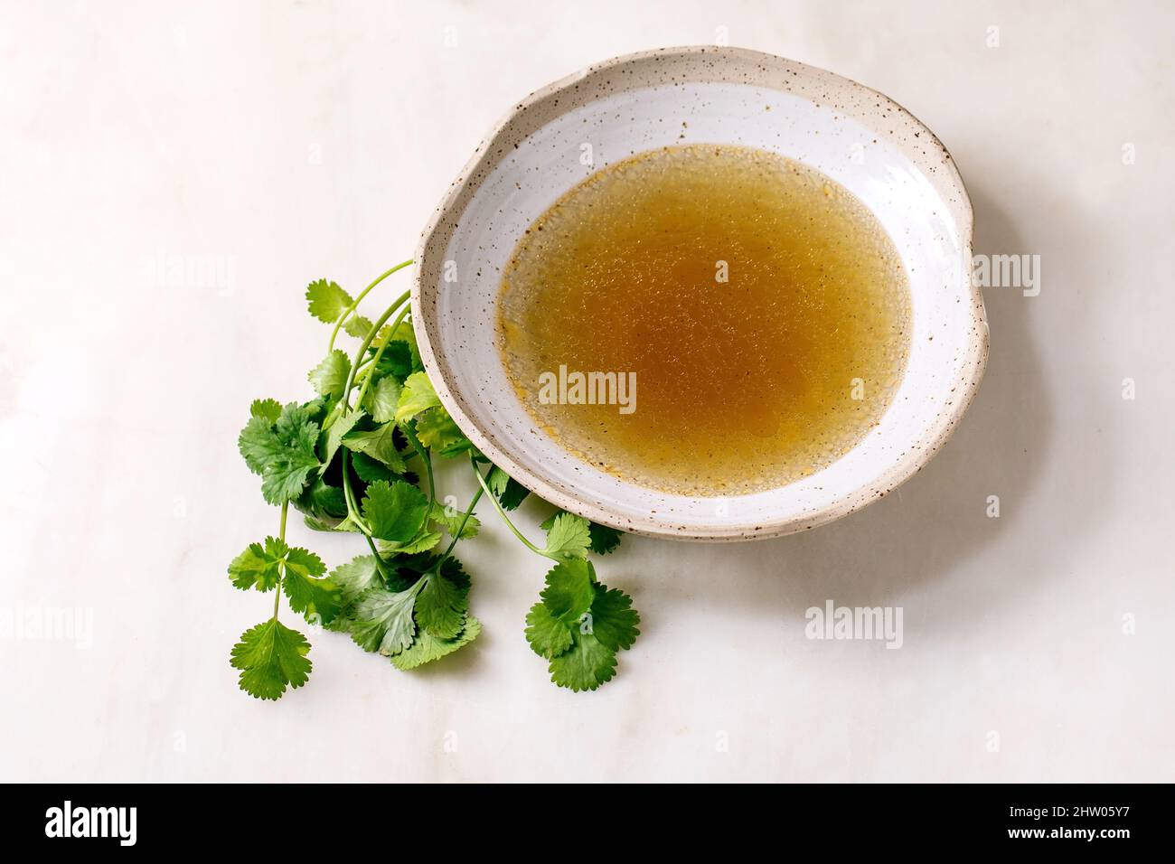 Clear homemade chicken or duck broth bouillon in ceramic bowl with