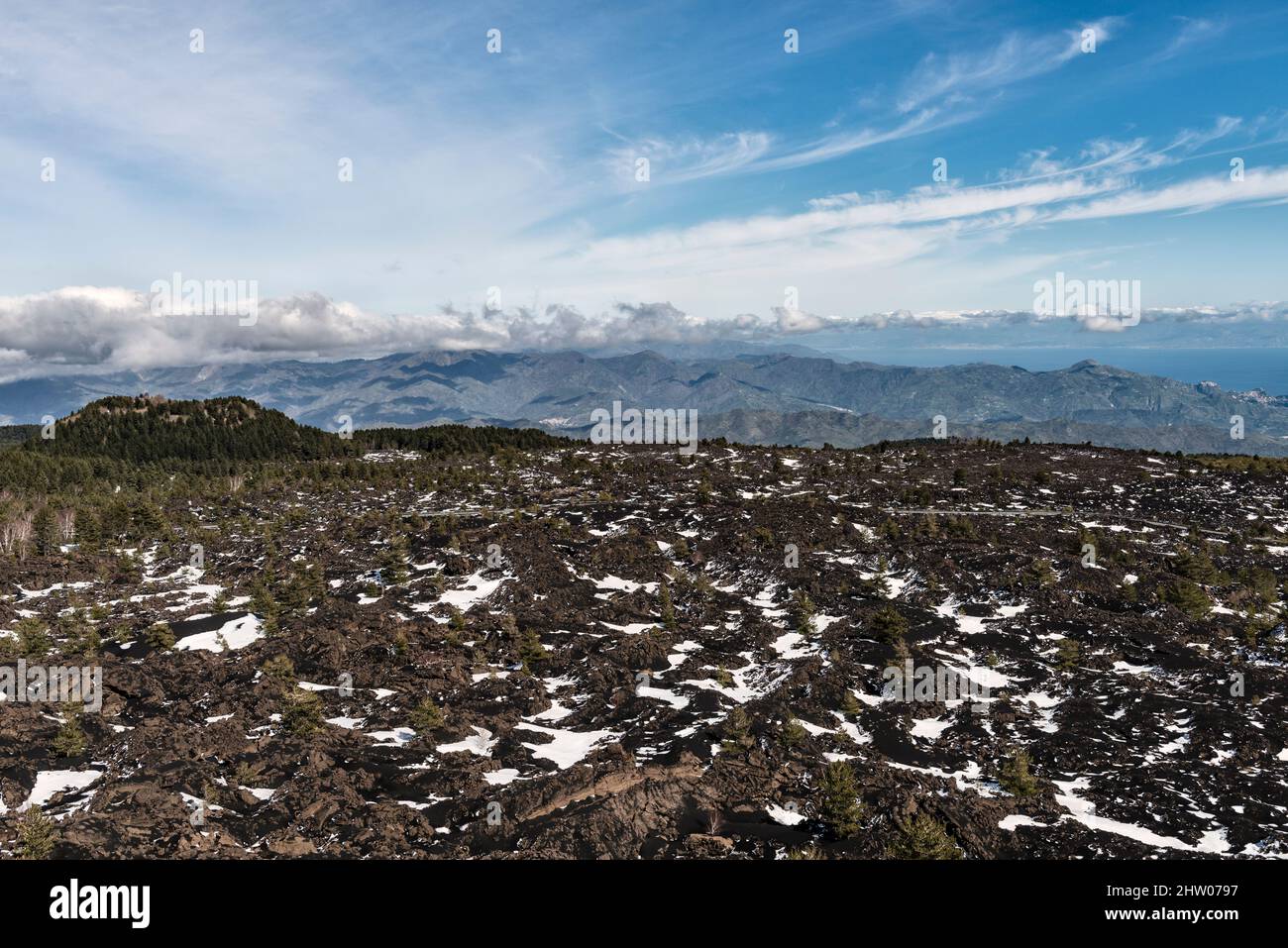 Looking over a lava field from the Monti Sartorius, a series of craters on the side of Mount Etna, Sicily. The Nebrodi Mountains lie in the distance Stock Photo