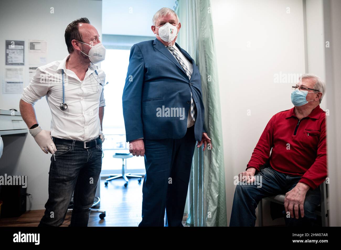 Krefeld, Germany. 03rd Mar, 2022. Physician Christian Einfalt (l) and Karl-Josef Laumann (CDU), Minister of Health of North Rhine-Westphalia, stand in the rooms of Einfalt's practice and talk to Rüdiger Bauer (r), who is getting vaccinated. The minister visited the family doctor's practice to get a picture of the vaccination process and the daily work routine. Credit: Fabian Strauch/dpa/Alamy Live News Stock Photo