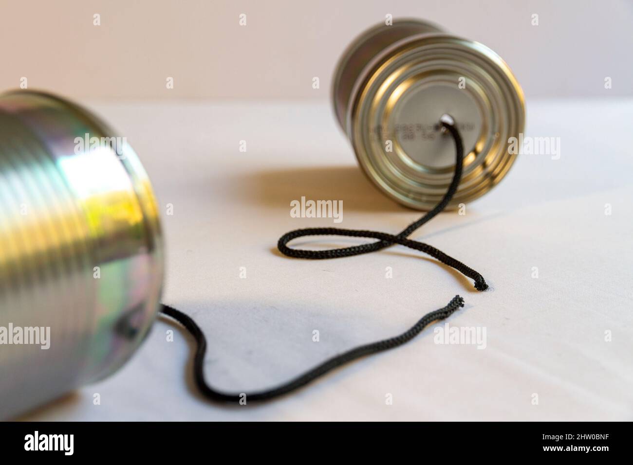 Two tin cans with a cut cord between them suggesting broken communication.Landscape orientation Stock Photo