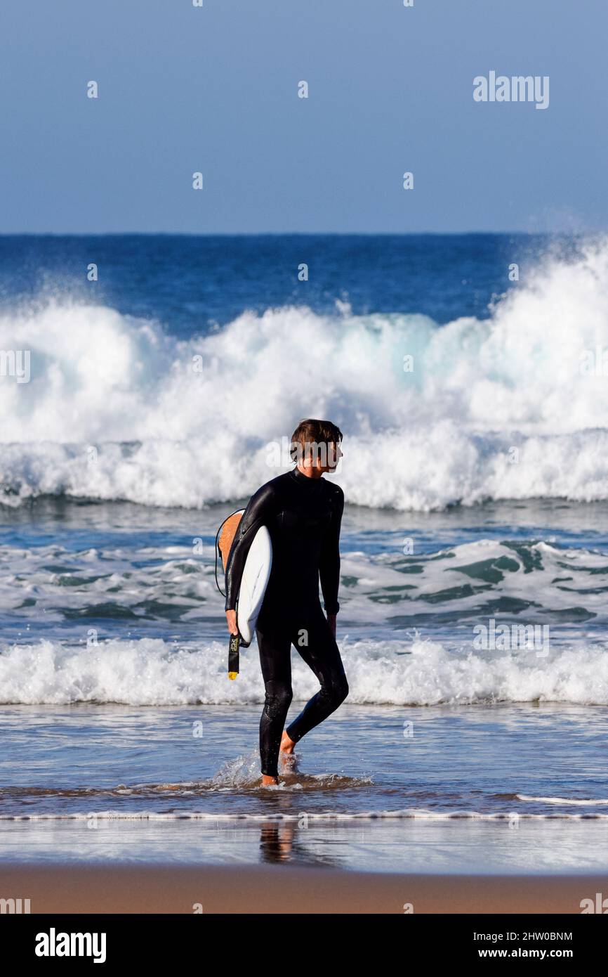 Male surfer with his board exiting the waves Stock Photo