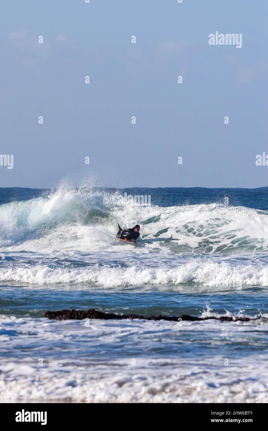Surfer coming to shore amongst waves Stock Photo
