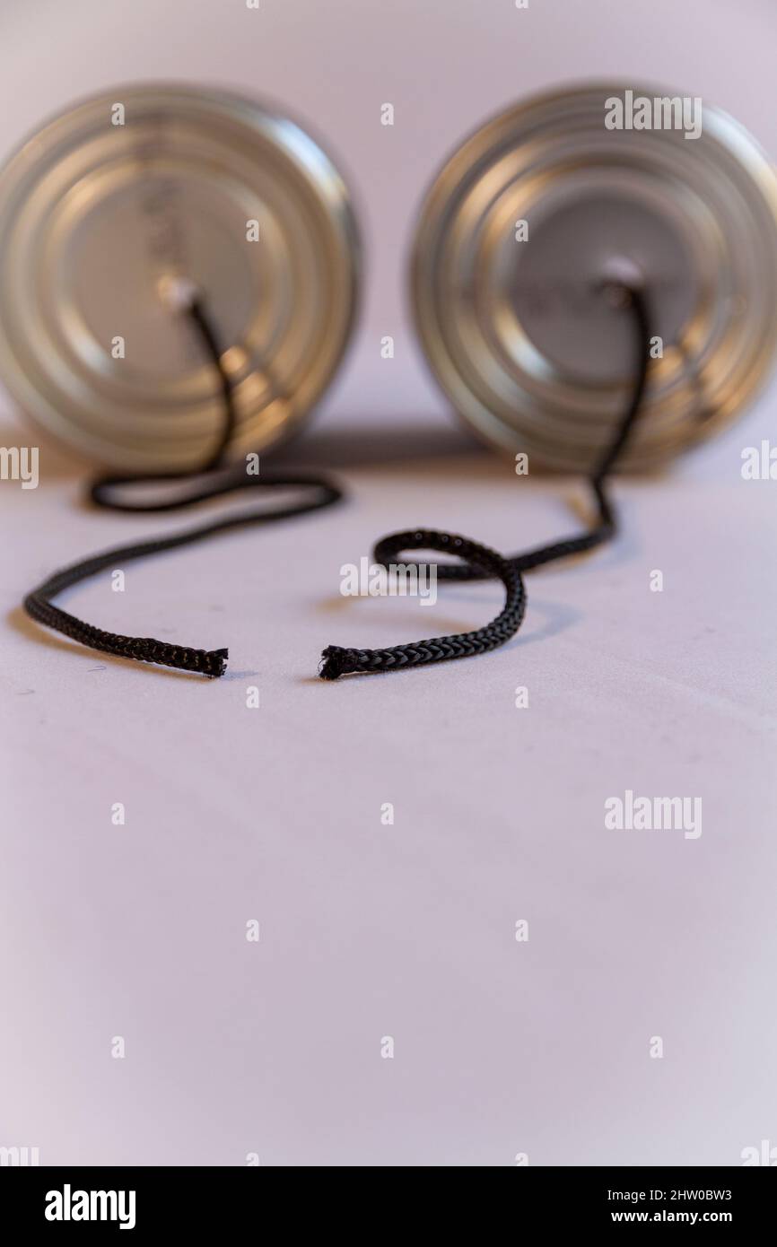 Two tin cans with a cut cord between them suggesting broken communication Stock Photo
