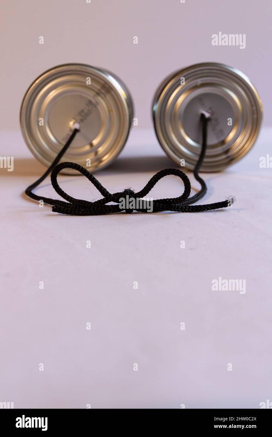 Two tin cans with a cord running between them tied with a bow Stock Photo