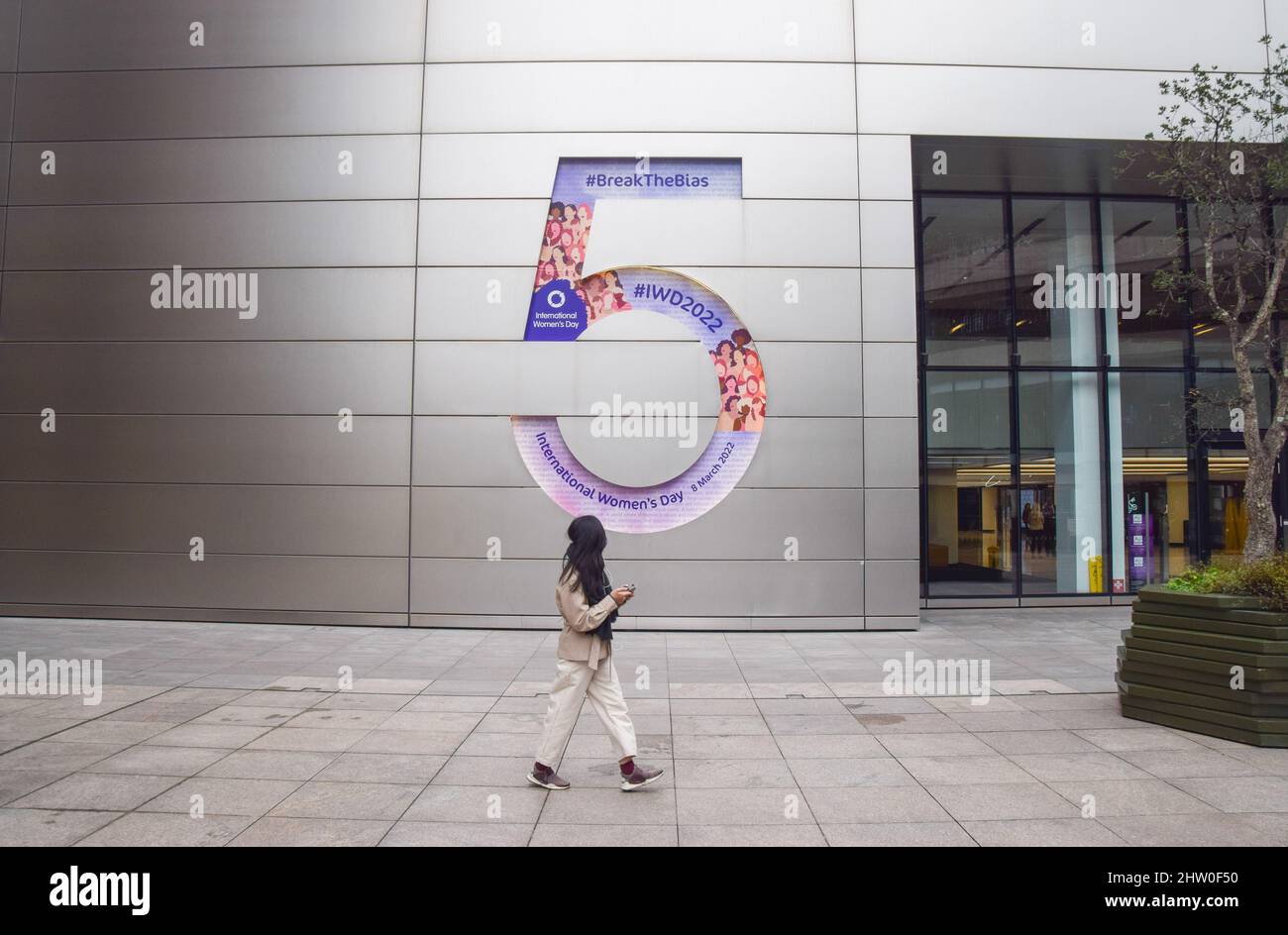 London, England, UK. 3rd Mar, 2022. A woman walks past the number 5 sign outside the headquarters of UBS at 5 Broadgate, which is adorned with a celebration of International Women's Day, taking place on 8th March. (Credit Image: © Vuk Valcic/ZUMA Press Wire) Credit: ZUMA Press, Inc./Alamy Live News Stock Photo