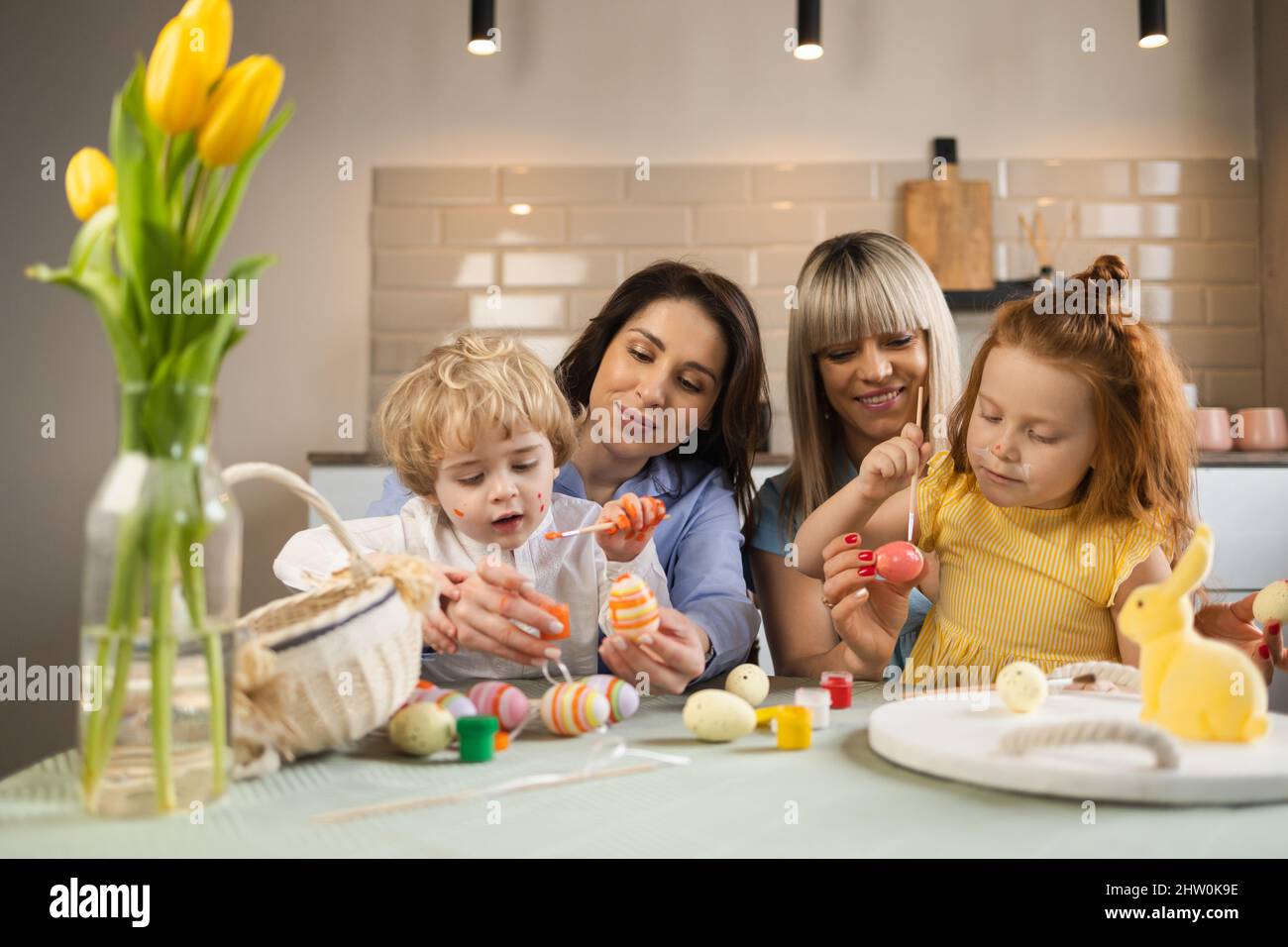 Two mother and her children decorating Easter eggs with paint Stock Photo