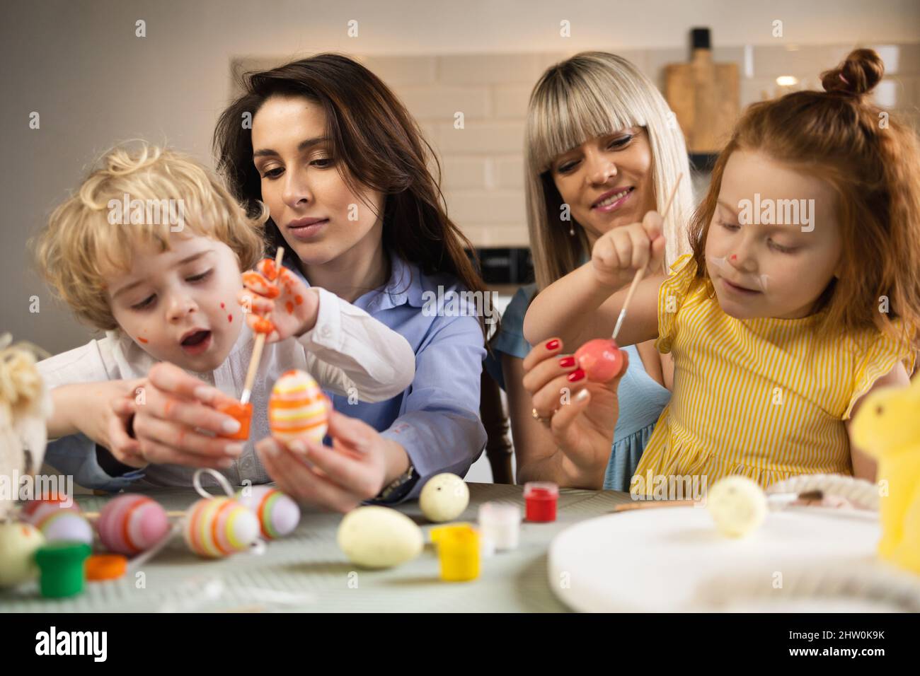 Two mothers with their children color eggs in preparation for Easter Stock Photo