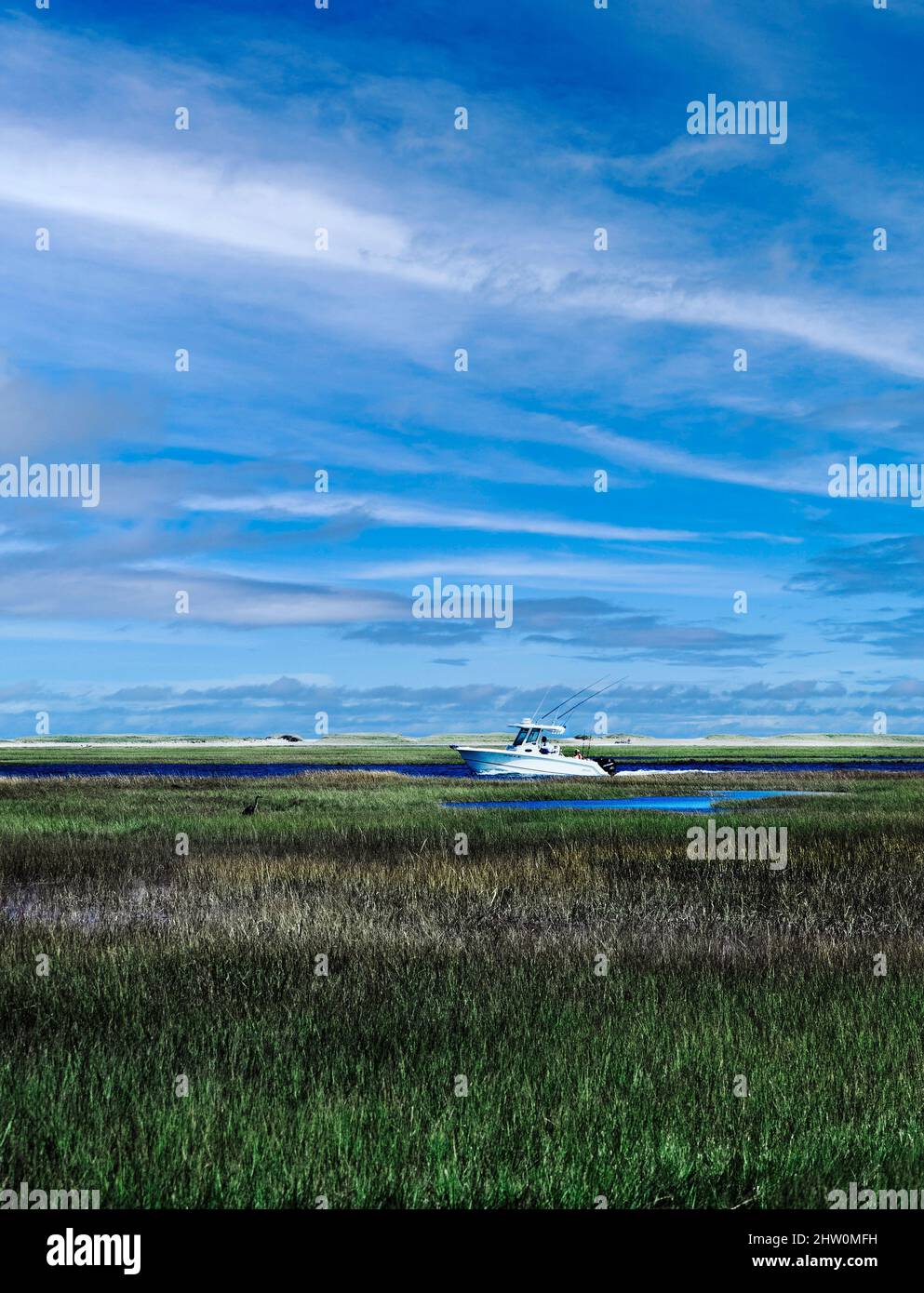 Sport fishing boat navigates through scenic salt marsh, Eastham, Cape Cod, Massachusetts, USA. Stock Photo