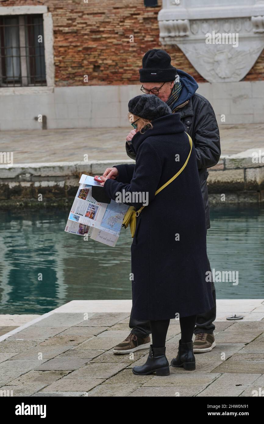 Elderly couple using both old and new technology to navigate around Venice Stock Photo