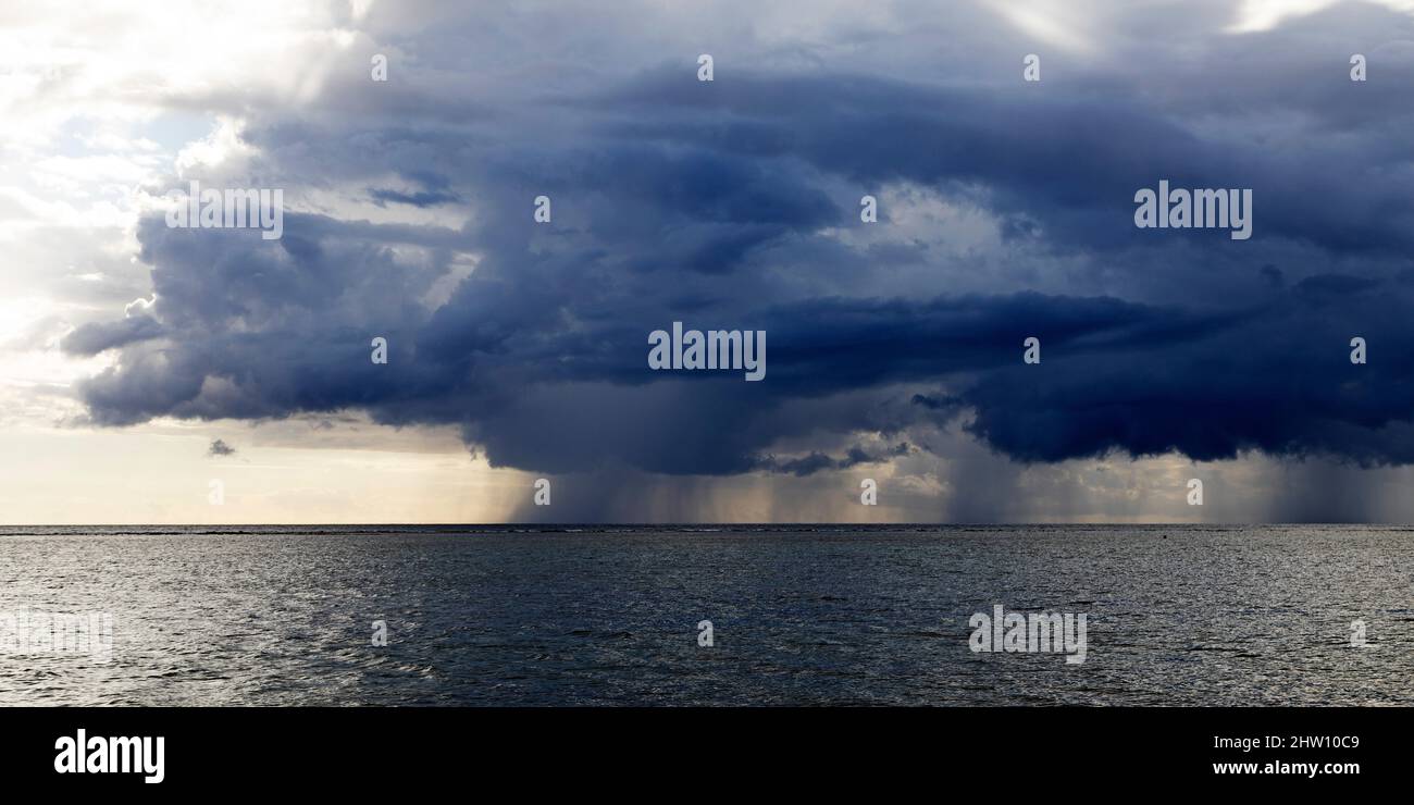 Rain clouds off the southwest coast of Mauritius. Rain falls into the Indian Ocean from the cloud. Stock Photo