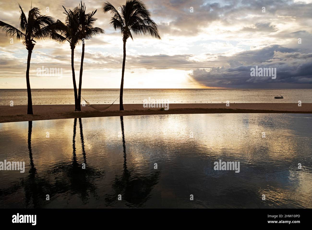 A hammock hangs from palm trees by an infinity pool by a beach at Flic en  Flac, Mauritius. Clouds gather offshore, over the Indian Ocean Stock Photo  - Alamy