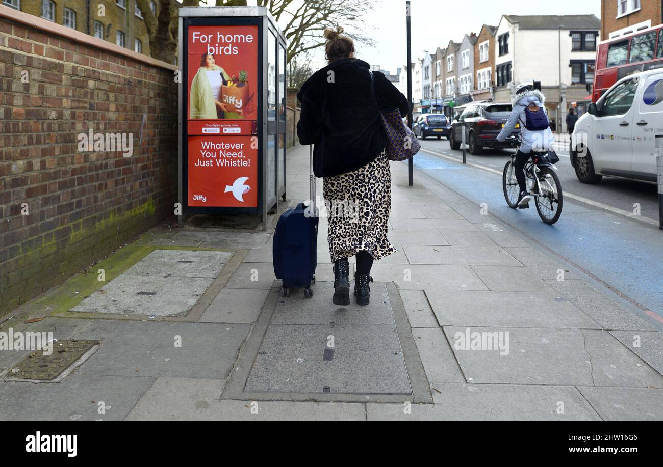 London, England, UK. Woman in the street with wheeled suitcase Stock Photo