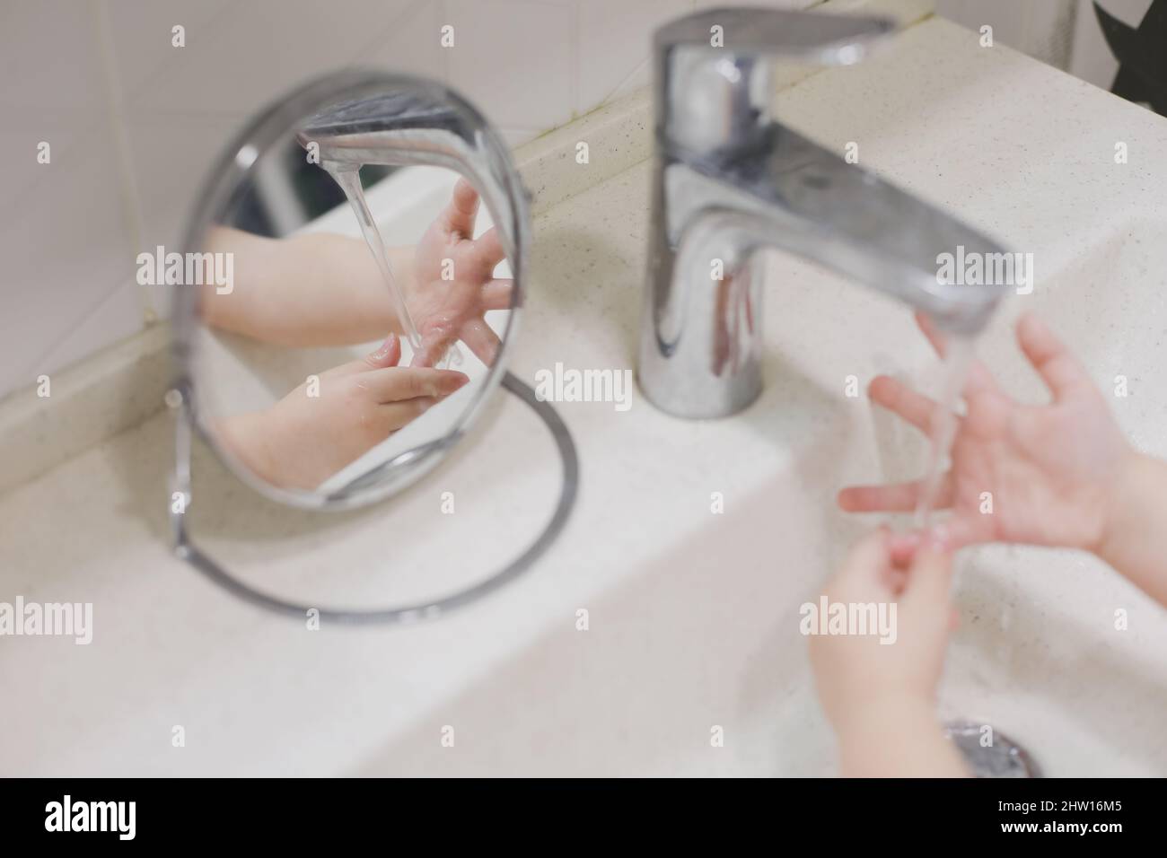 child washing hands under the tap water in the bathroom. kid's hands under stream of water. Stock Photo