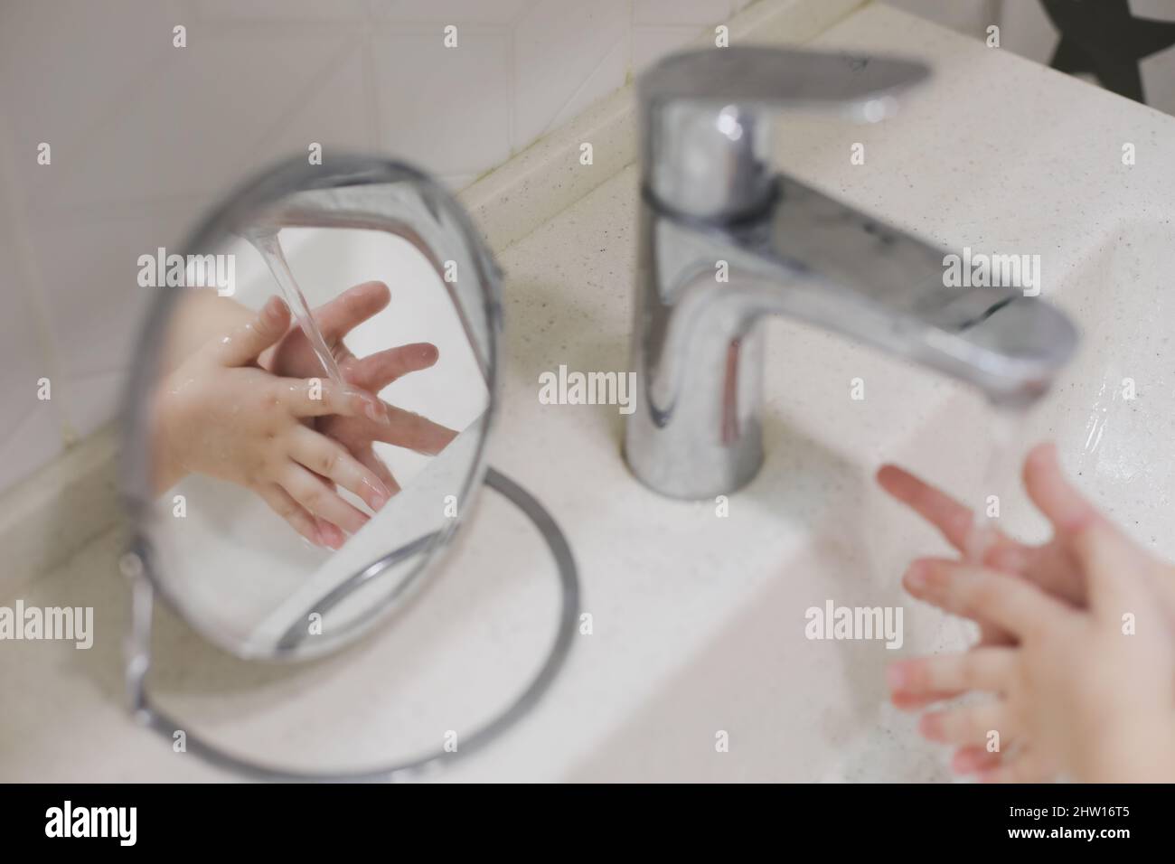 child washing hands under the tap water in the bathroom. kid's hands under stream of water. Stock Photo