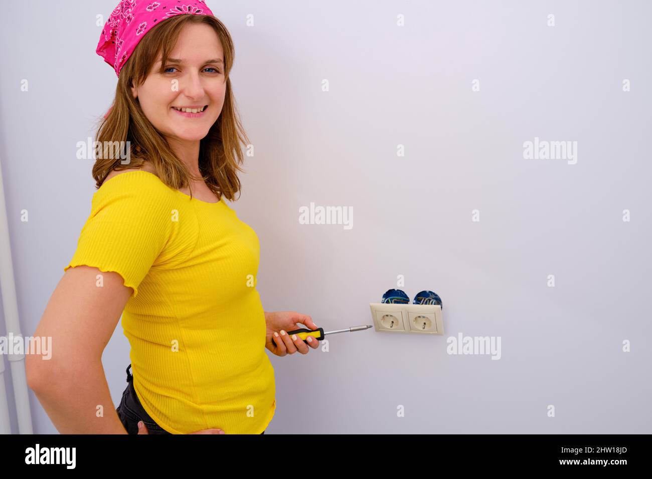 Woman smiling holding a screwdriver in her hands to repair electrical