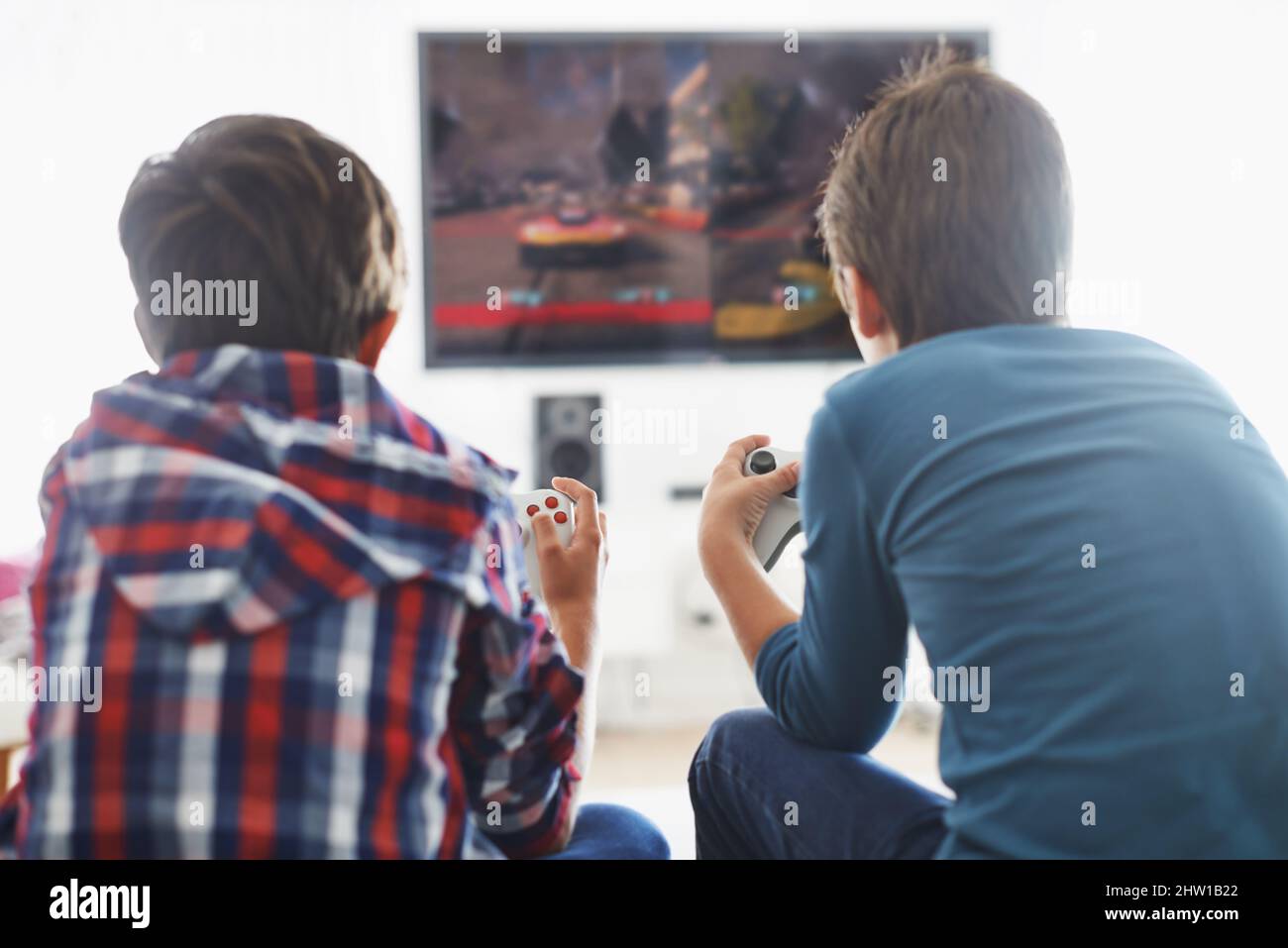 Game Time. Rearview shot of two boys playing a video game in the living room. Stock Photo