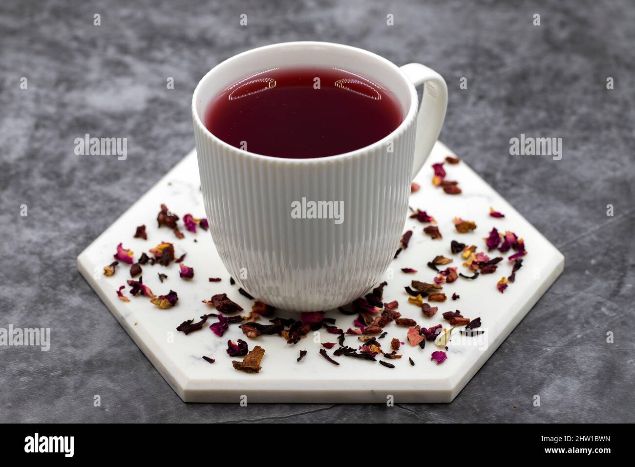 Pomegranate tea on a dark background. Herbal tea prepared with pomegranate seeds, pomegranate peel, hibiscus, clove, cinnamon particles. Stock Photo