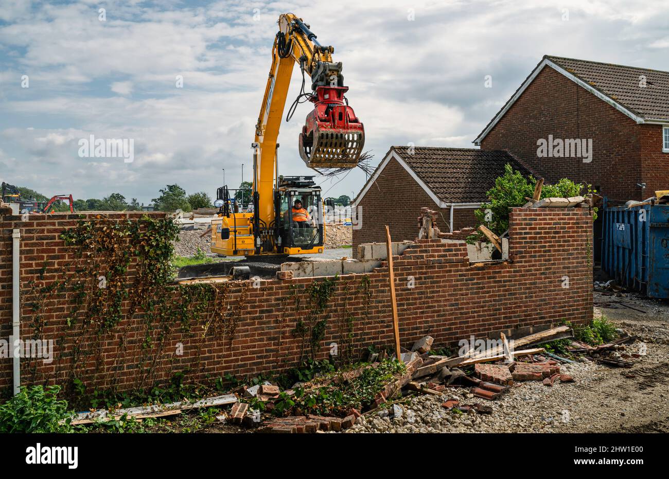 Heavy duty machinary with operator demolish garage and house to make way for new supermarket development near Minster Way, Beverley, UK. Stock Photo