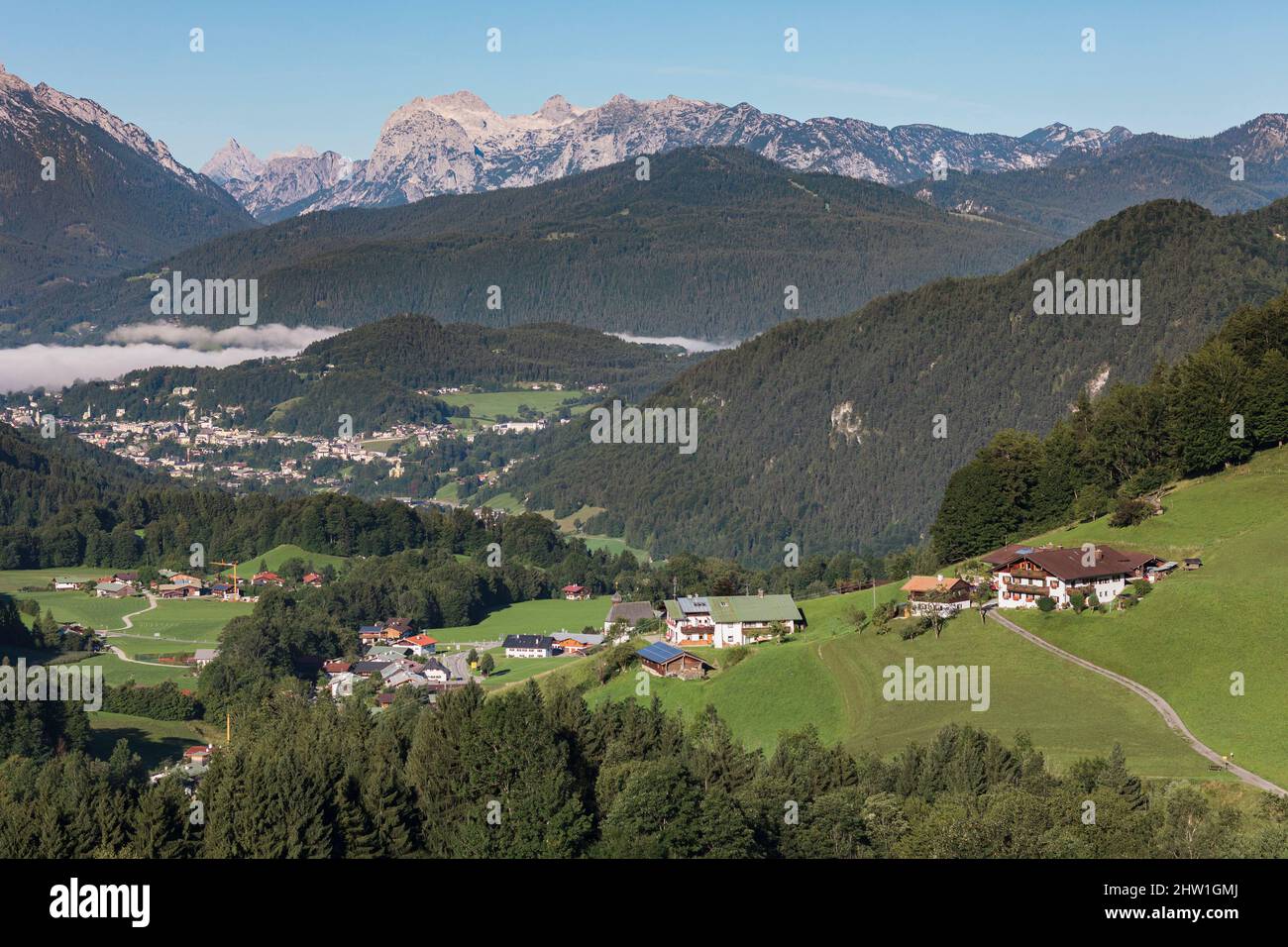 Germany, Bavaria, Upper Bavaria, Obersalzberg, alpine landscape, chalets, forest and rocky ridges under the morning sun, mist over the village of Oberau down in the valley Stock Photo