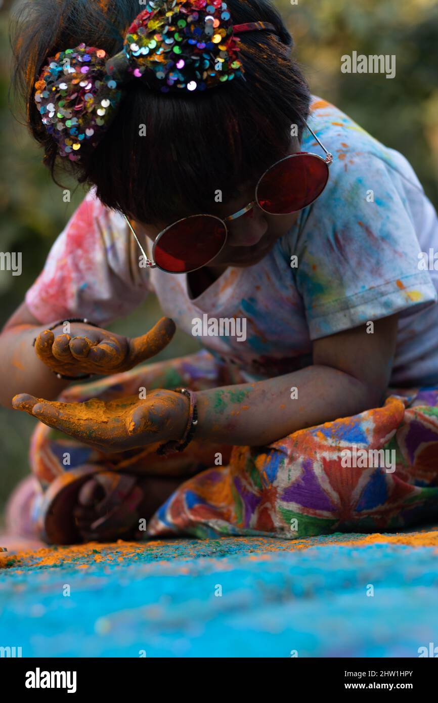 Colorful Holi Theme - Portrait Of Cute Indian Kid Wearing Round Colored Shades And Pinted In Holi Color Powder Called Rang Gulal Stock Photo