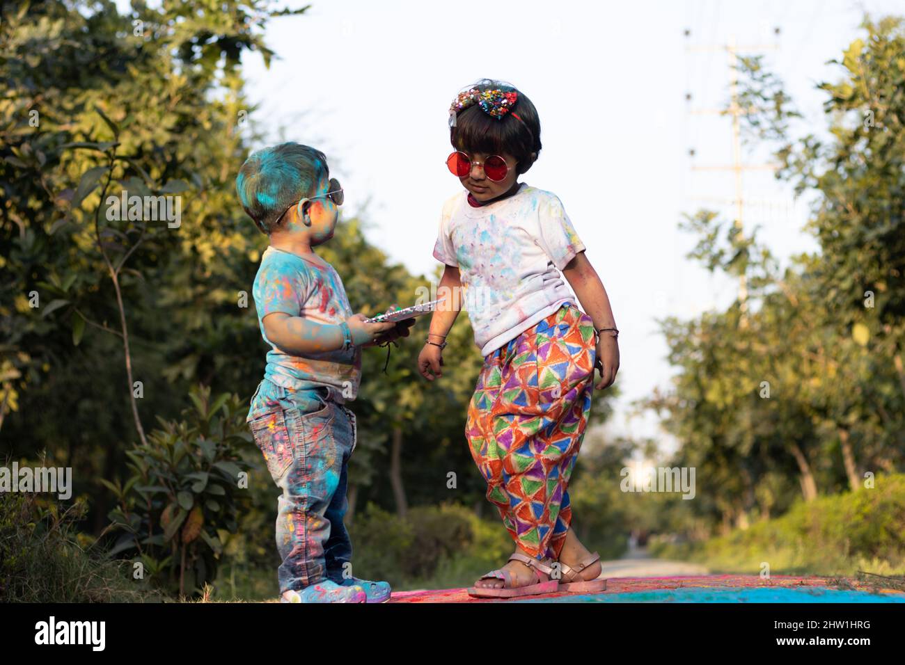 Happy Asian Indian Kids Boy And Girl Enjoying The Festival Of Colors With Holi Color Powder Called Gulal Or Rang Stock Photo