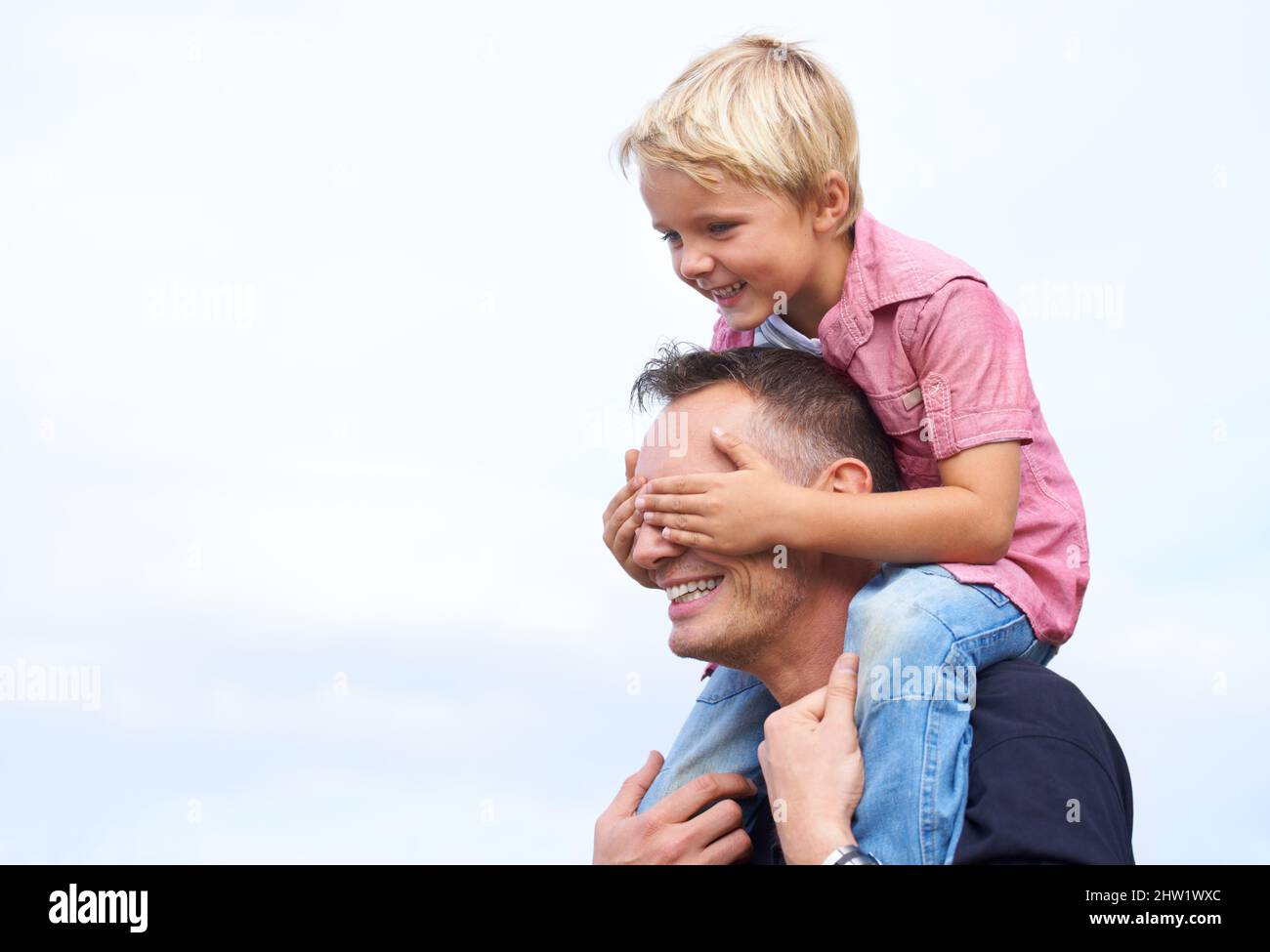 Day with dad. Shot of a playful father giving his son a piggyback outside. Stock Photo