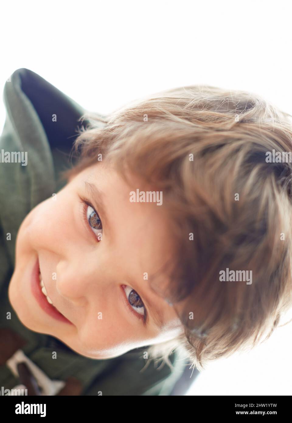 Up to some mischief.... A young boy leaning over to look at the camera. Stock Photo