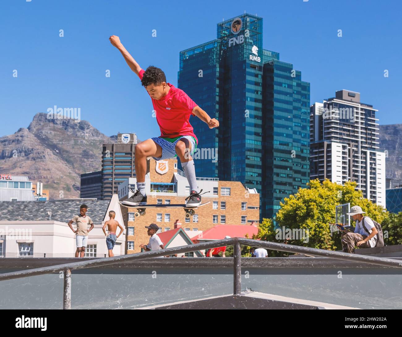Cape Town, South Africa, 26th February - 2022: Man rides skateboard in air with city centre as backdrop. Stock Photo
