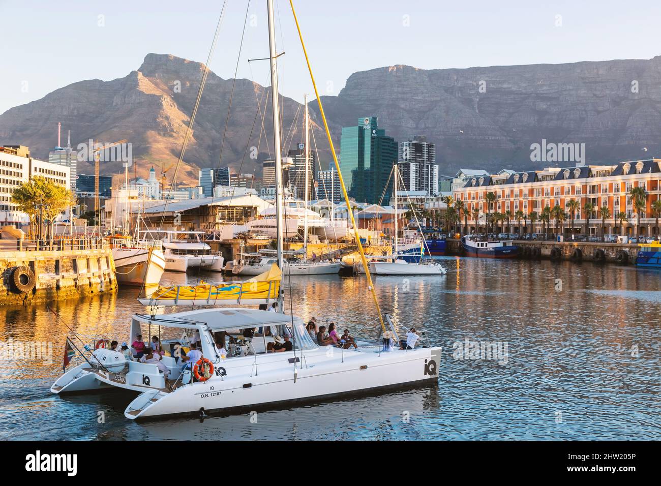 Cape Town, South Africa, 26th February - 2022: Yacht sails across harbour with city in background. Stock Photo