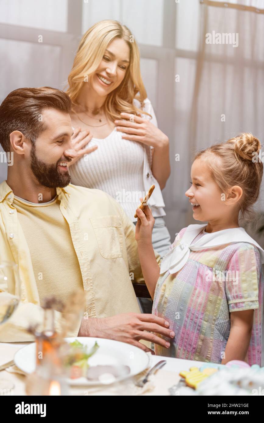 happy girl showing easter cookie to pleased parents,stock image Stock Photo