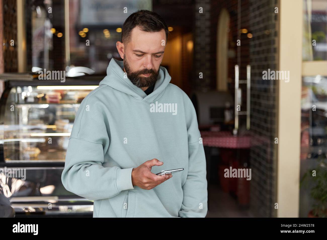 Bearded man in casual clothes using his smartphone Stock Photo