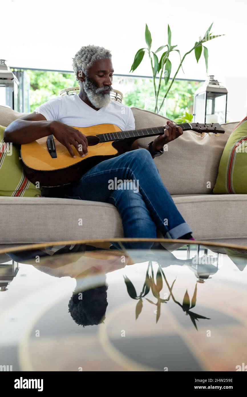 African american senior man playing acoustic guitar while sitting on ...